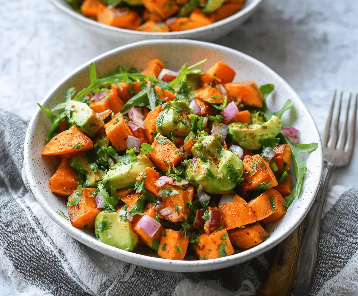 Creamy sweet potato salad with fresh avocado slices, garnished with herbs, served in a white bowl for a healthy, delicious meal.