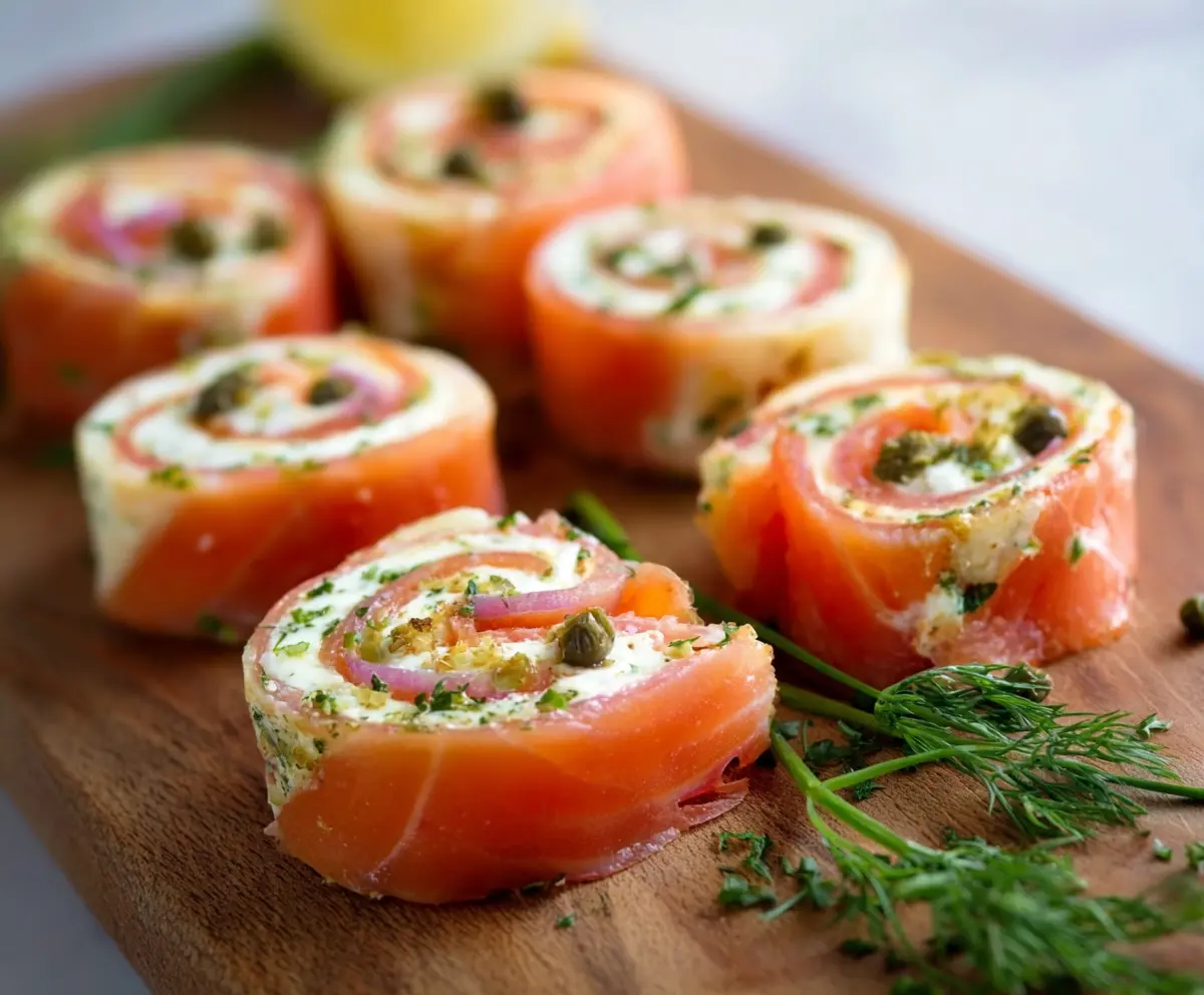 Delicious smoked salmon pinwheels with cheese and herbs on a serving platter.