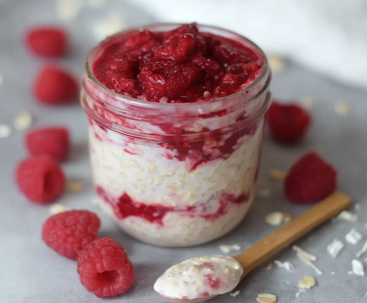 Creamy Raspberry Cheesecake Overnight Oats topped with fresh raspberries and a dash of mint, perfect for a nutritious breakfast.