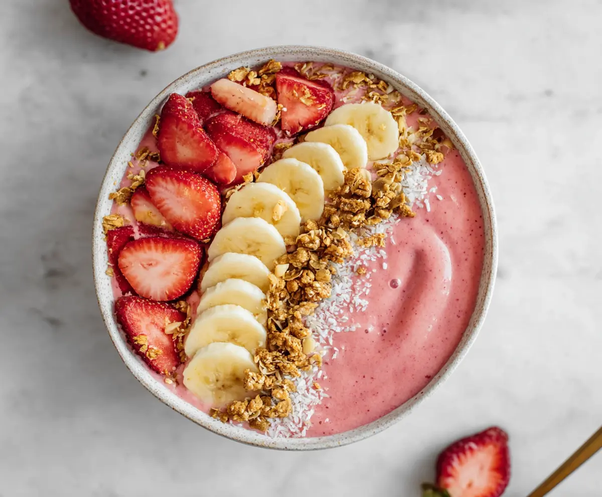 Vibrant strawberry banana smoothie bowl topped with fresh fruit and granola, perfect for a healthy breakfast.