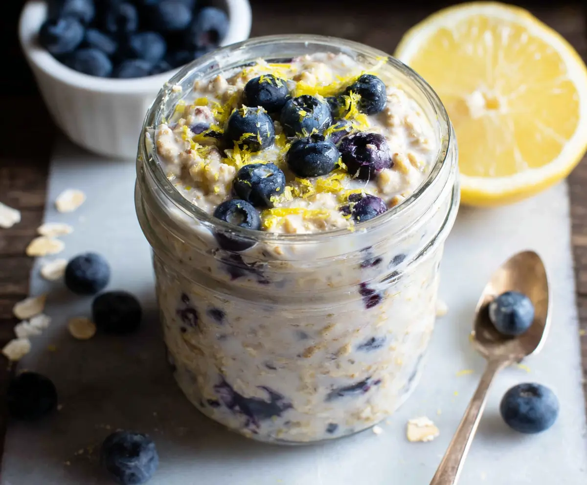 Creamy blueberry lemon overnight oats in a glass jar topped with fresh blueberries and lemon zest.