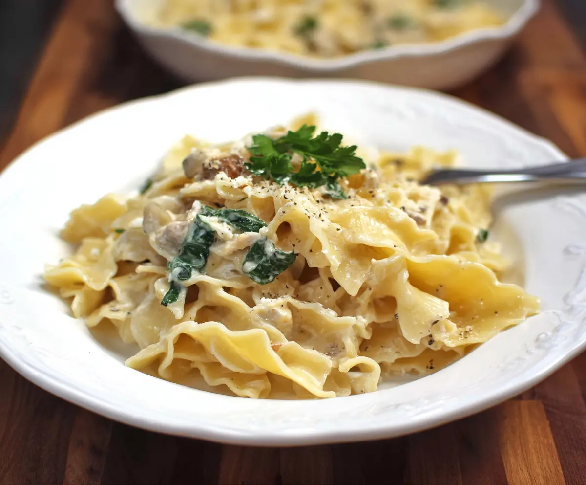 Creamy blue cheese pasta garnished with fresh herbs in a white bowl.