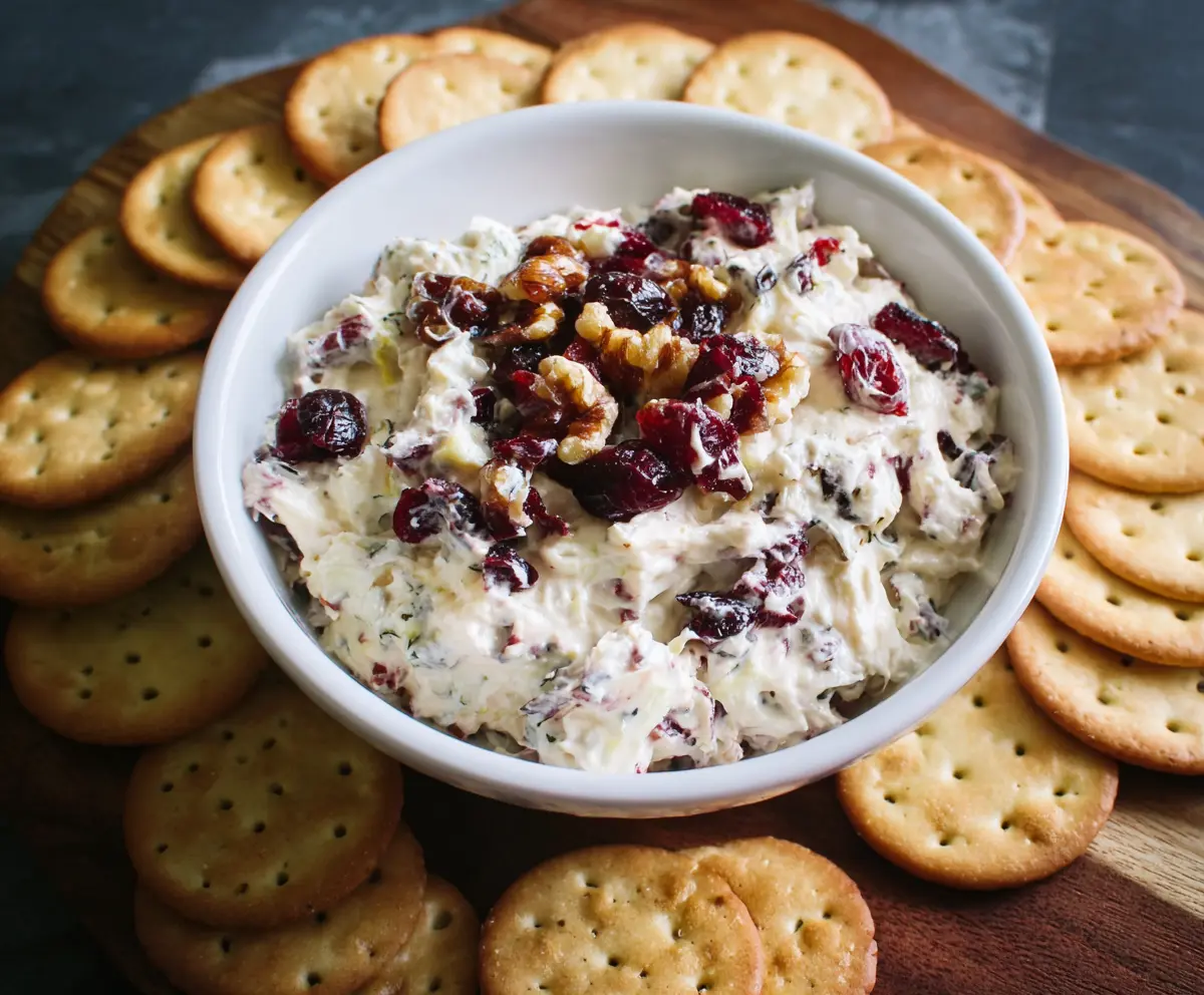 Creamy cranberry walnut cream cheese dip served with fresh fruit and crackers for a festive snack.