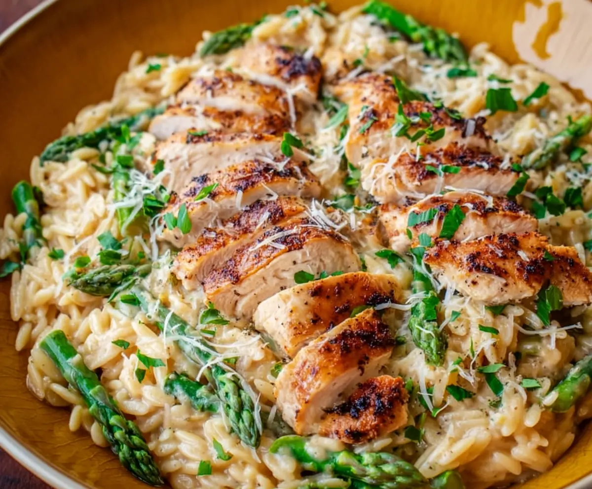Creamy Parmesan orzo with grilled chicken and fresh asparagus on a plate
