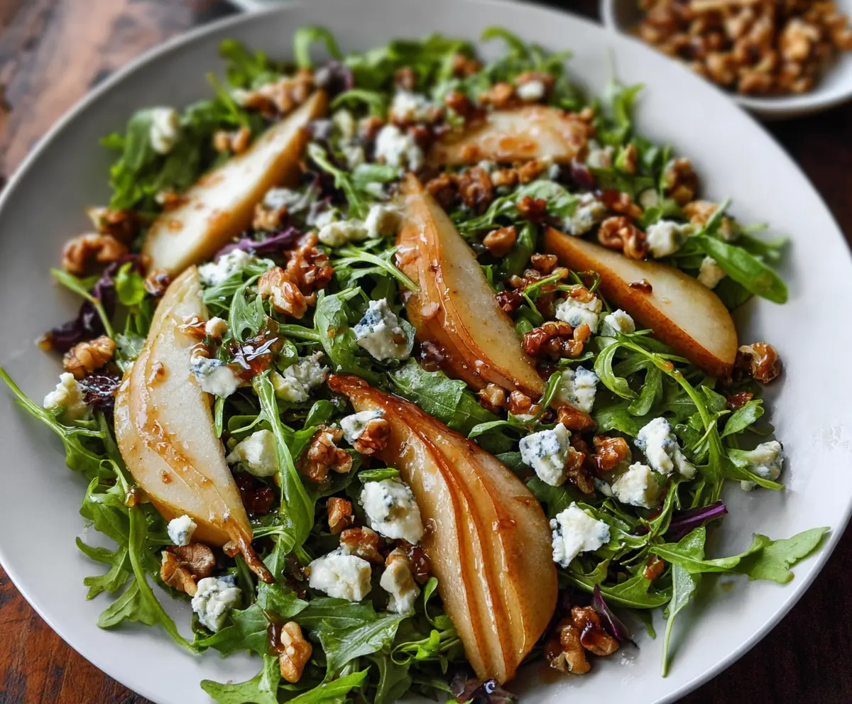 Fresh arugula and sliced pears salad topped with blue cheese crumbles and walnuts, perfect for a healthy meal.