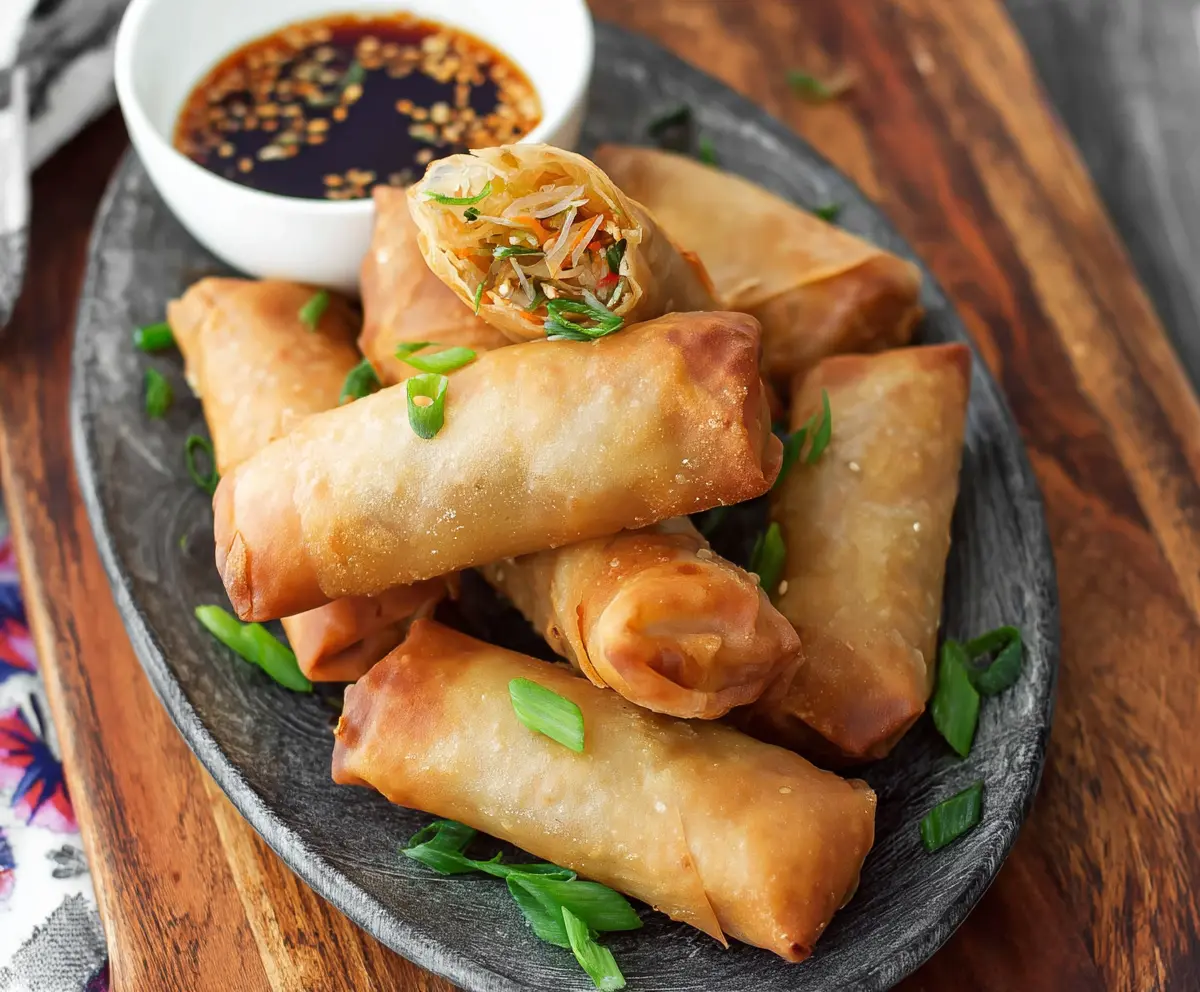 Crispy baked Chinese vegetable spring rolls served with dipping sauce on a plate.