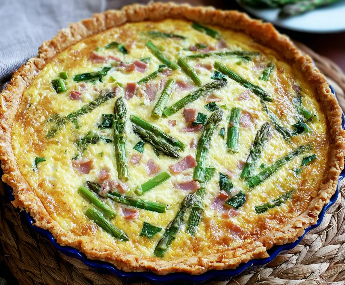 Delicious ham and asparagus quiche served on a white plate, ideal for brunch or lunch.