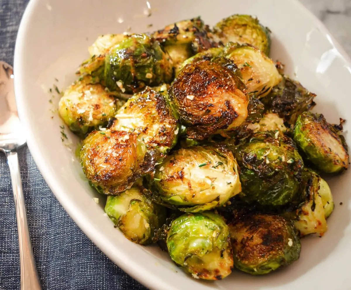 Delicious roasted Brussels sprouts with crispy edges and caramelized seasoning on a white plate.